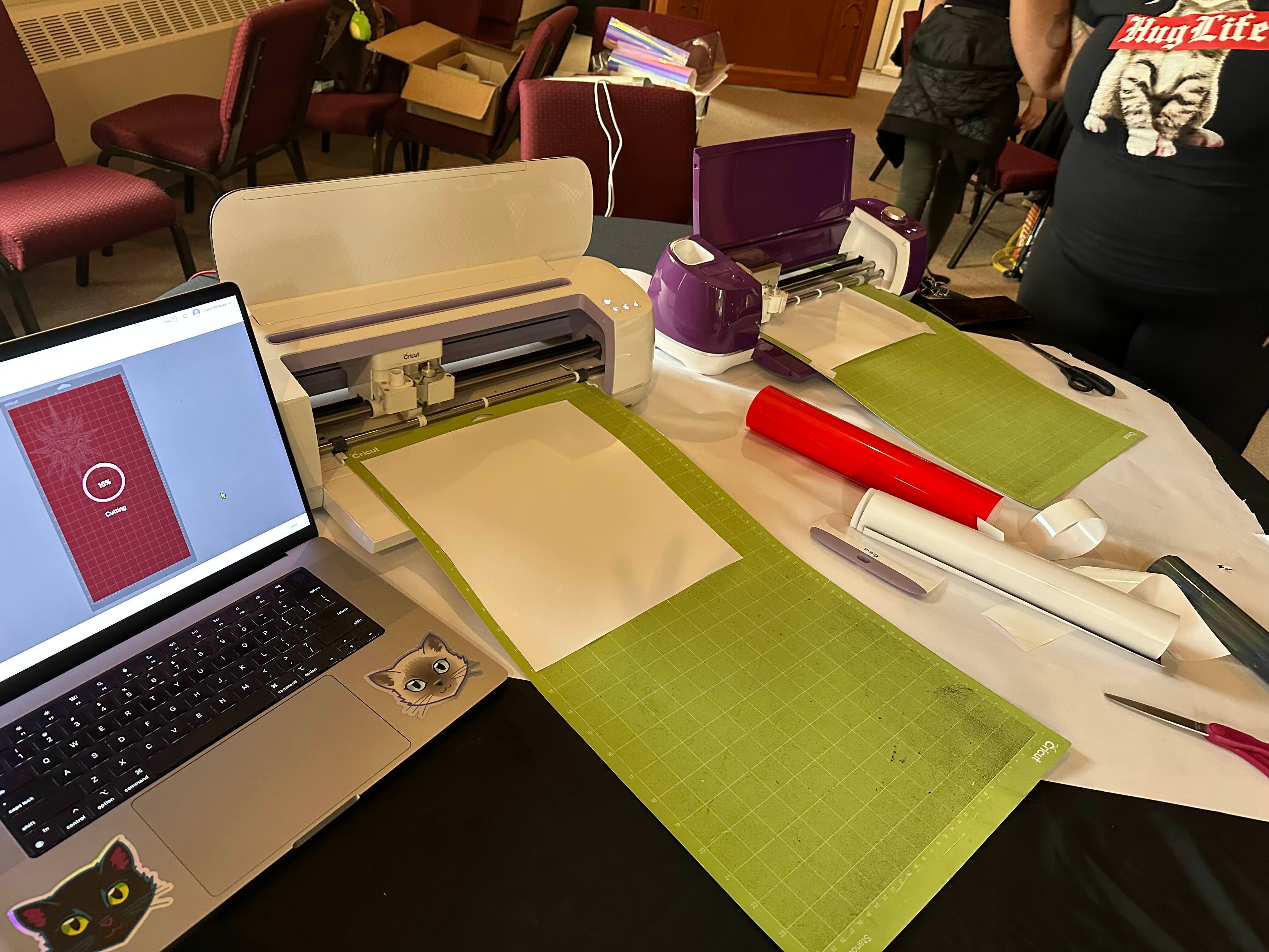 collection of cricut cutters, laptop, and other vinyl pressing supplies