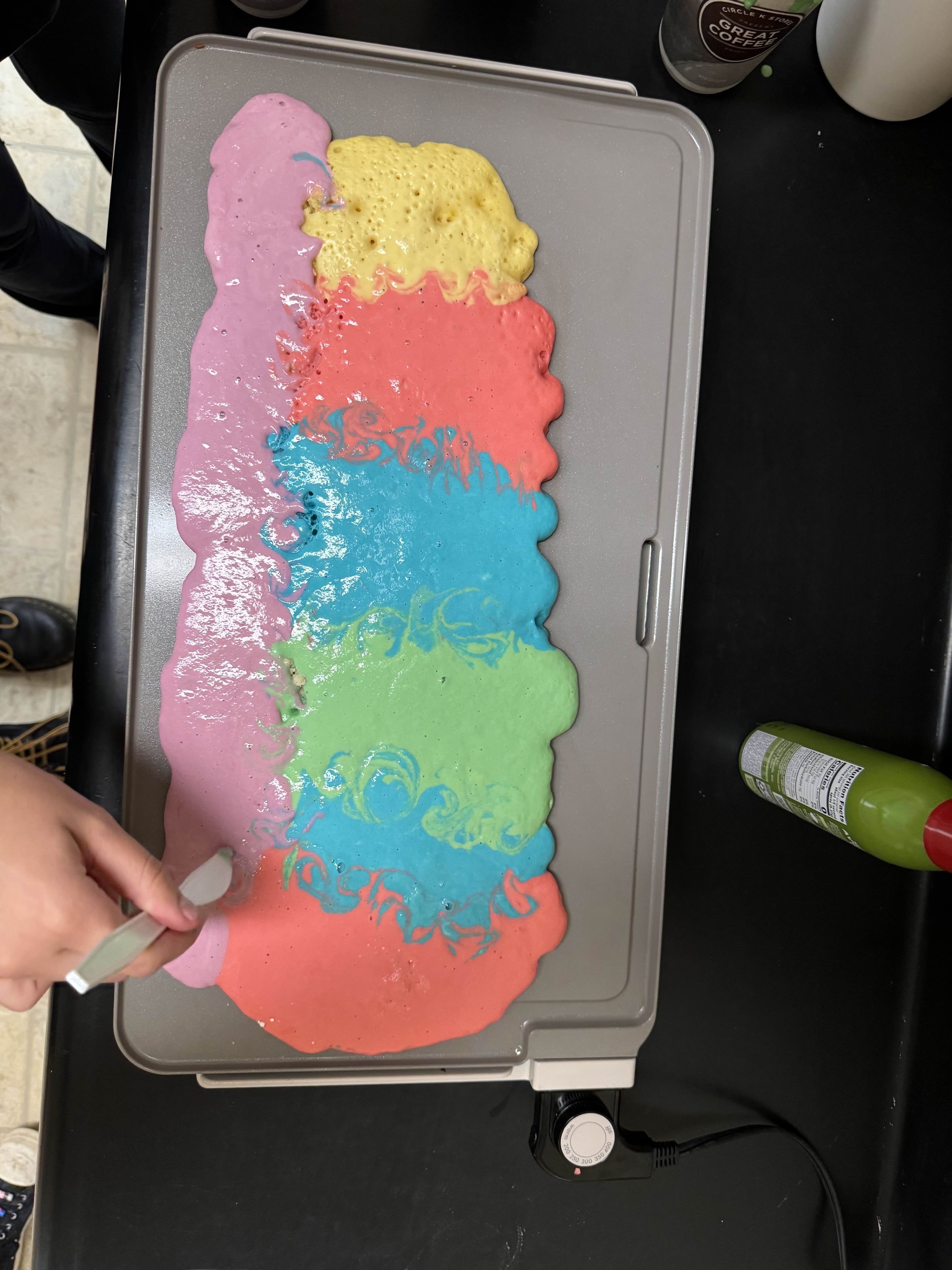 electric griddle sitting on counter with various colors of pancake batter