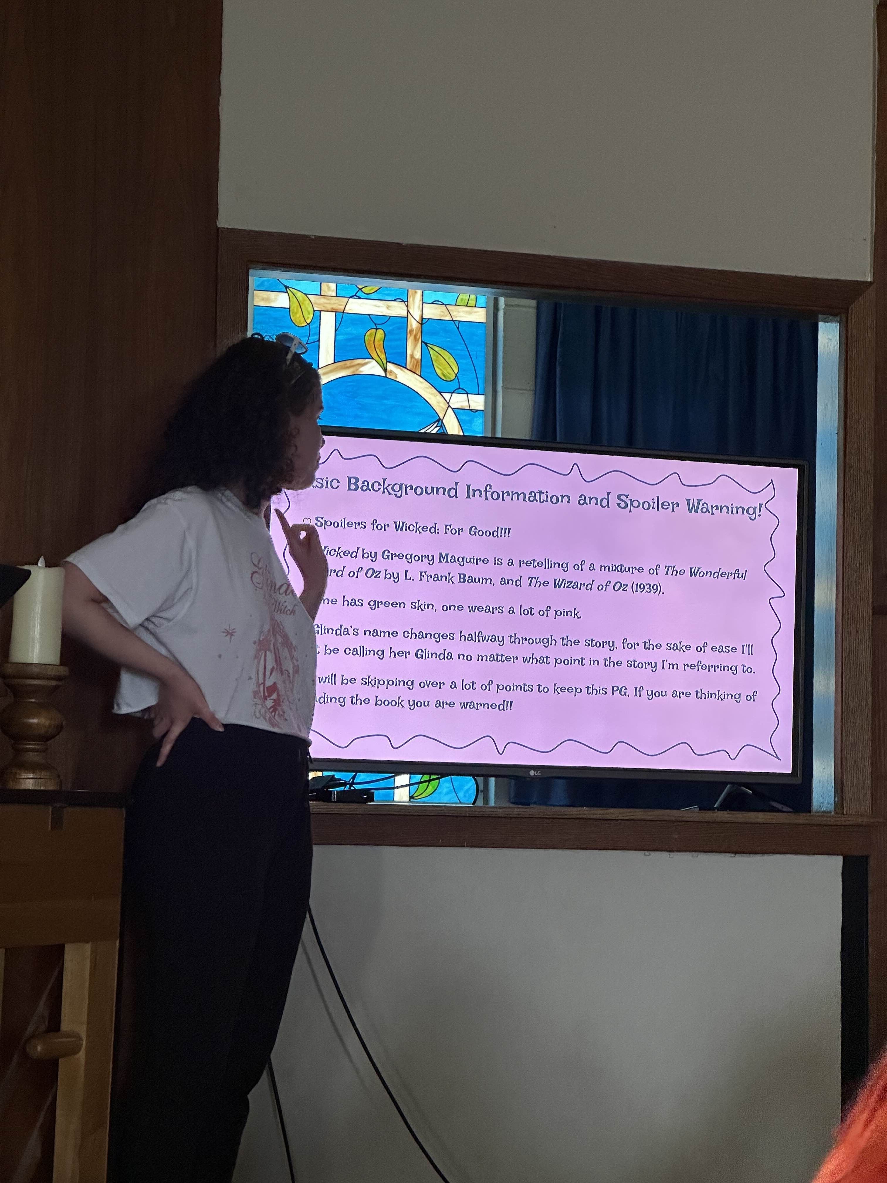 person standing next to TV reading off a slideshow presentation